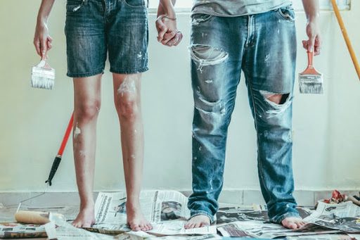 A homeowner couple covered in paint after painting their interior walls.