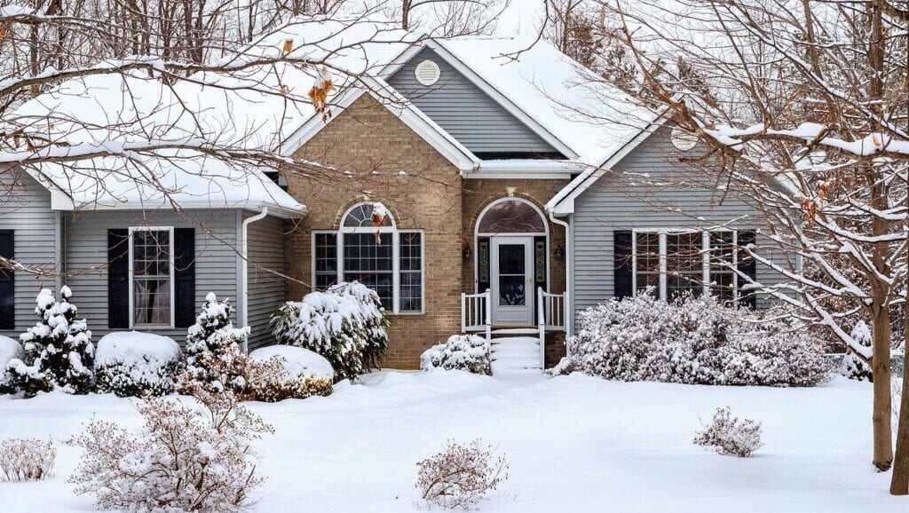 A two-story home and front lawn covered in snow.
