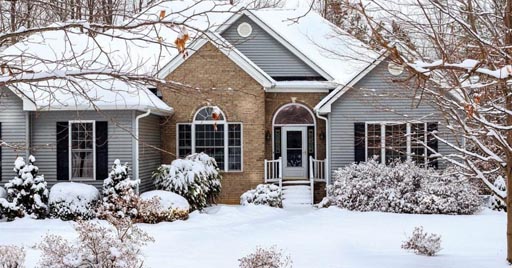 A two-story home and front lawn covered in snow.