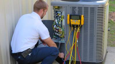A HVAC technician inspects the air conditioning fan electronics.