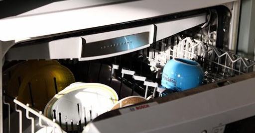A dishwasher loaded with plates and cups.