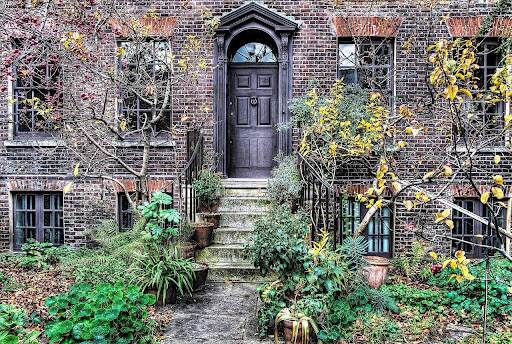An English-style garden grows in front of a brick house.
