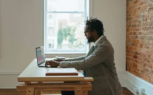 A person sits at a large table working on a laptop.