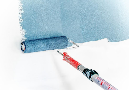 Blue paint being applied to a wall with a paint roller.
