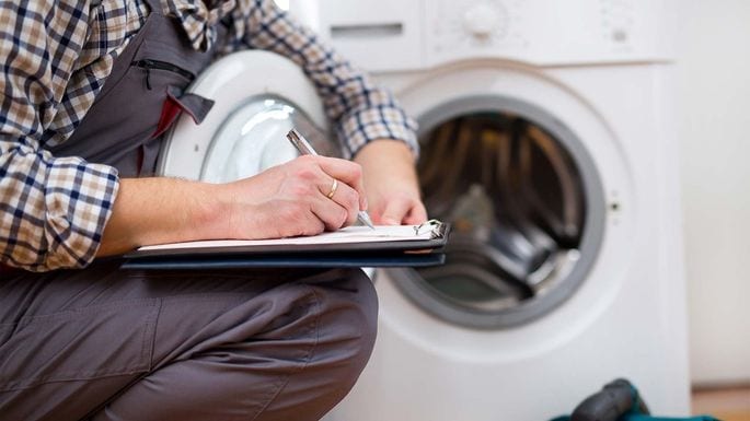 A repair professional inspects a washing machine.