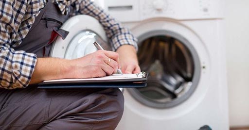 A repair professional inspects a washing machine.