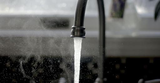 Steaming water comes out of a kitchen sink faucet.